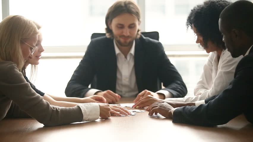 Multi-ethnic business group assembling jigsaw puzzle together at conference table, company leader helping team in decision making, teambuilding activity, contribution in common goal, teamwork support Royalty-Free Stock Footage #30832678