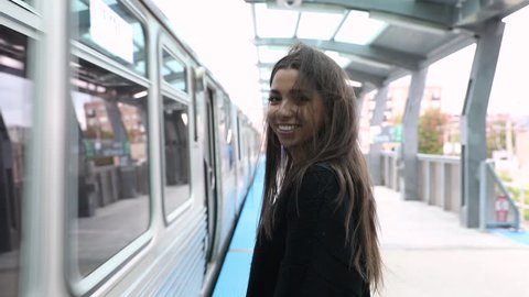 Girl waiting for train and smiling, slow motion. Beautiful young woman at subway station, lifestyle and travel concepts