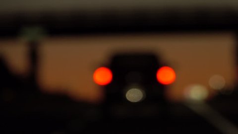 POV Driver with bad vision driving behind black SUV car on highway at dusk. Person with poor eyesight drives on freeway at dawn in early morning. FPV Blurry sight, vision with high dioptre after dark