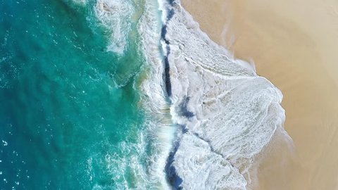 Aerial view waves break on white sand beach at sunset. Sea waves on the beautiful beach aerial view drone 4k shot.