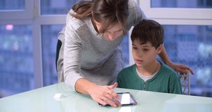Mother and son child use a tablet 4k video. Woman parent and boy kid touch mobile PC screen. Family and technology