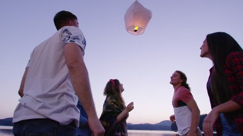Diverse Group Of Young Men And Women Holding A Sky Lantern Smiling And Releasing it Camping Youth Togetherness Romantic Getaway Concept Slow Motion Shot On Red Epic W 8k