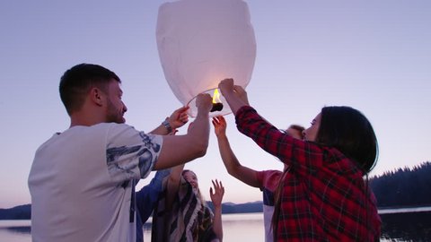 Attractive Multiracial Group Of Young Friends Around Sky Lantern At Dusk on Lake Shore Happiness In Nature Concept Slow Motion Shot On Red Epic W 8k