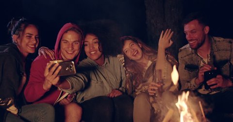 Attractive Multiracial Group Of Young Friends Around Burning Camping Bonfire In The Woods Taking a Selfie And Smiling Nature Tourism Technology Concept Slow Motion Shot On Red Epic W 8k