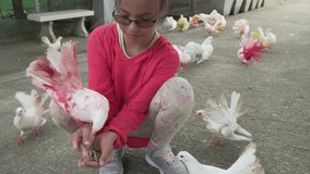 Young girl feeds the ornamental pigeons with multi-colored feathers stock footage video