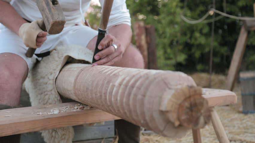 Medieval carpenter strike on the chisel with hammer