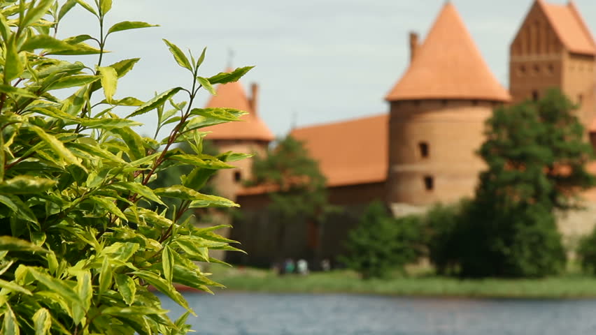 Old red stone castle. On the shore of beautiful lake. Crowd of people , tourist walking around historical  sight. 10