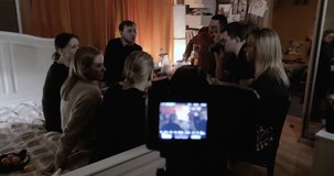 Shooting video of friends gathering together. Adults relaxing, talking and having drinks while children having fun in next room