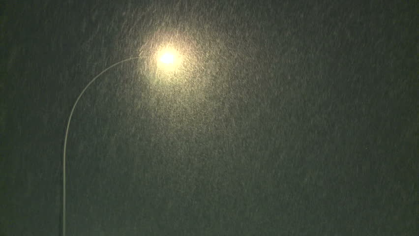 Snowfall at night time under a street light