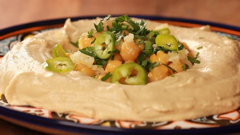Hummus plate preparation with chickpeas and parsley and paprika and lemon juice.