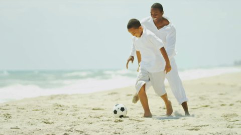African American parent enjoying vacation with son playing football