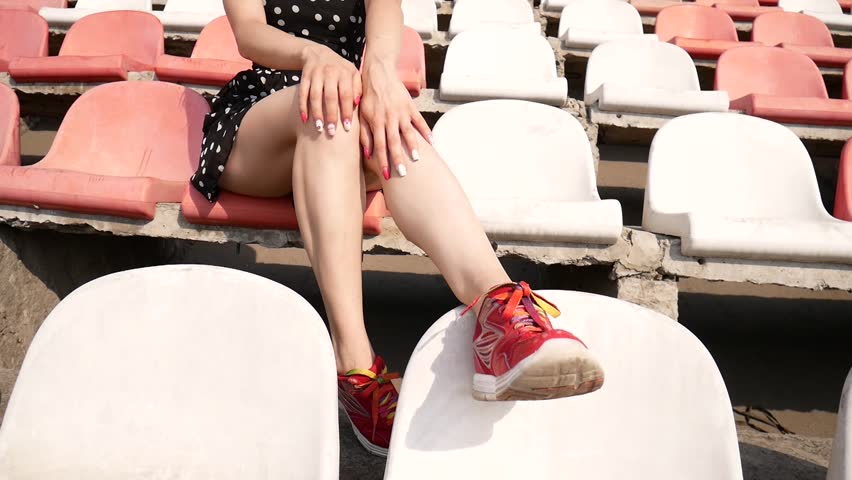 Beautiful girl in a dress in the stands of the stadium.