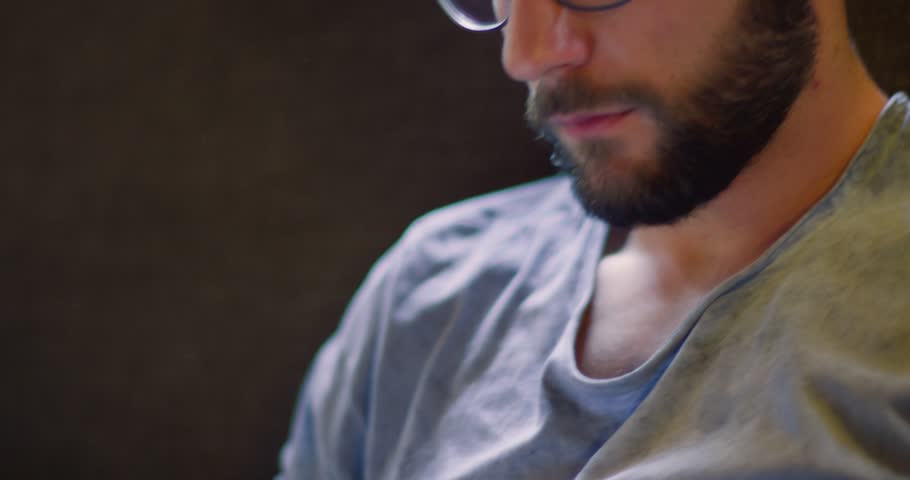 Youg millennial man relaxing reading magazine newspaper at home in casual dressing. 4k video