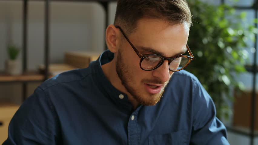 Portrait of tired, sick businessman in the stylish glasses taking pill during work time in the modern office. Taking medecine. Close up