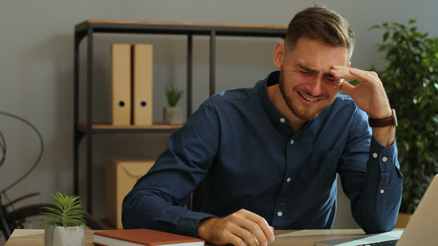 Young sad desperate man crying during his work and usining napkins to removing tears in the office. Close up Protection, europe infected, Workplace, healthcare, covid-19, attention, face, pandemic  | Shutterstock HD Video #30873268