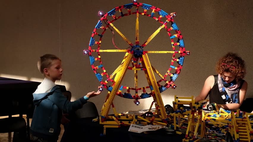 Russia, Moscow, September 2017 - A girl with a child assemble a Ferris wheel out of LEGO