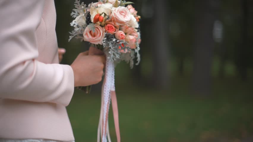 Beautiful wedding bouquet in the hands of the bride in autumn. Slow motion close up shot.