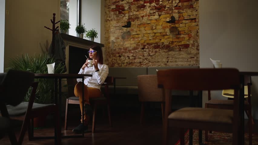 Smartphone girl using app on phone drinking coffee smiling in cafe. Beautiful multicultural young casual female professional on mobile phone. Mixed race Asian Caucasian model.