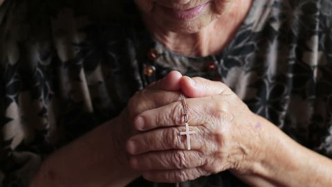 Old woman praying to God. Daily traditional Catholic devotional of an old lady or woman