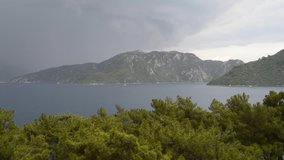 A storm with rain, thunderstorm and lightning looming on the Mediterranean Sea coast with mountains covered with forests near the town of Marmaris, Turkey. Video with accelerated shooting  