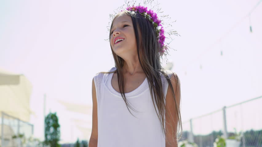 Happy little girl looking at sky and smiling at camera on the bay bar. 4K