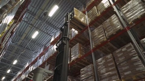 BELARUS, MINSK - AUGUST 14, 2017: Forklift in the warehouse raises a boxes toward the top shelf. Warehouse materials. Shelves in the warehouse, August 14 in Minsk.