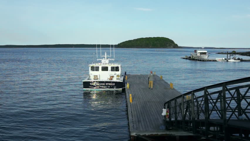 Bar Harbor, USA - June 8, 2017: View of dock and boat with man in downtown village in summer climbing, getting, walking aboard