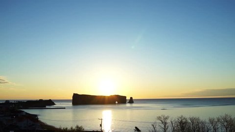 Famous Rocher Perce rock in Gaspe Peninsula, Quebec, Canada, Gaspesie region at sunrise and sun reflection path, flare, glade and warm soft sunlight