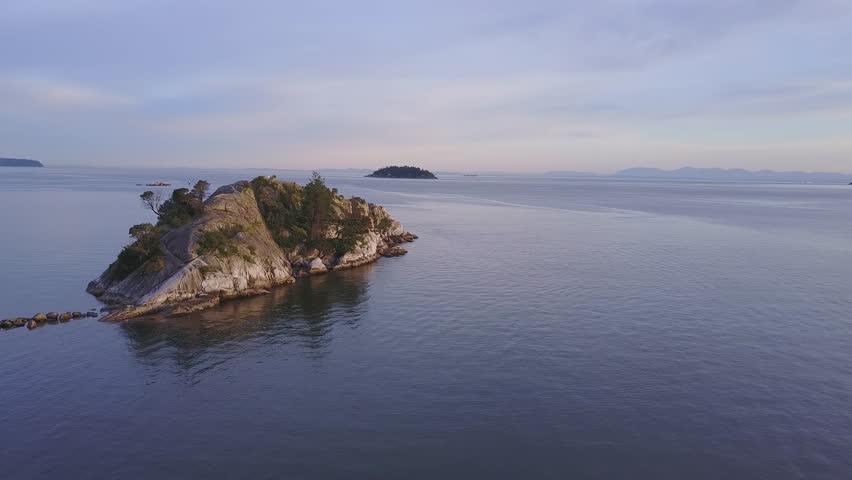Aerial view on the beautiful rocky shore during a colorful sunset. Video taken in Whytecliff Park, Horseshoe Bay, West Vancouver, British Columbia, Canada.