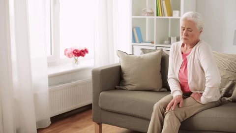 old age, health problem and people concept - senior woman suffering from pain in leg at home