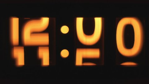 stop motion of an old style flip clock lit up and passing through 12 hours