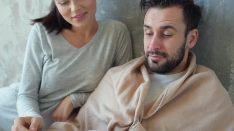 Close up of ill man letting his wife thermometer