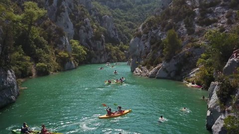 Aerial view of kayaks in a river canyon of Gorges du Verdon, France. View of kayaking and swimming in Verdon Gorge in the summer sunshine. 4k drone footage of rocky canyon landscape teal blue water.