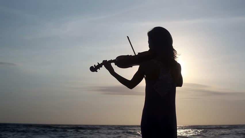 Silhouette of violinist playing on violin at ocean beach