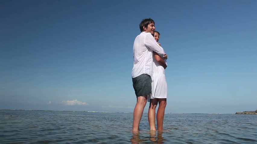 Happy man embracing his girlfriend and standing in ocean