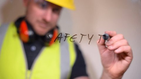 Health and safety officer with safety equipment writes safety tips on a clear glass screen