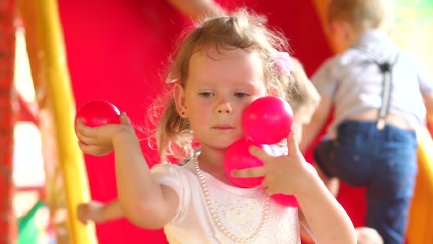 Charming girl throws pink balls playing in the children