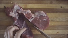 A Chef is cutting meat on a cutting board	