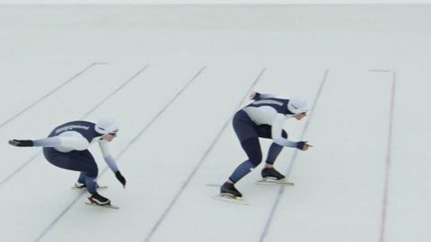 High angle shot with slowmo of professional sportswomen in spandex full-body covering suits speed skating in ice rink Arkivvideo