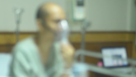 Defocus male patient making inhalation with nebuliser in room