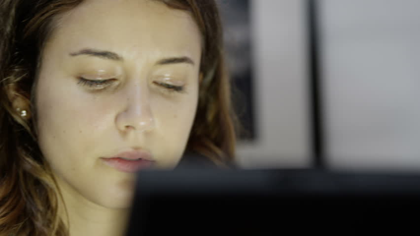 Close up of a very tired young woman who is working on a computer late into the night. She is over-worked and it is easy to see the emotional strain on her face.  Royalty-Free Stock Footage #3092761