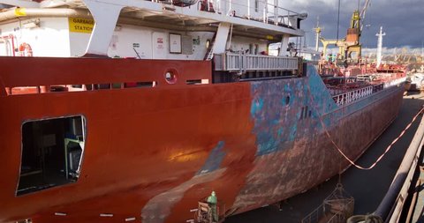 Workers repair and paint vessel at floating dock at the shipyard. Ship painters at work. Boat dyeing timelapse 4k video.