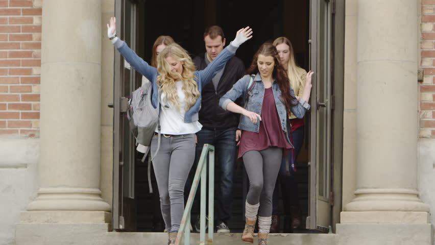 Group of college leaving a building together on a college campus.
