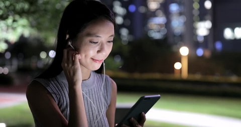 Woman talk to smart phone in the park at night