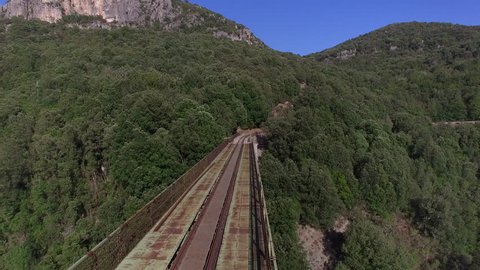 Stunning aerial POV  shot of train running an old railroad going deeper into the mountains, Sardinia, Italy.