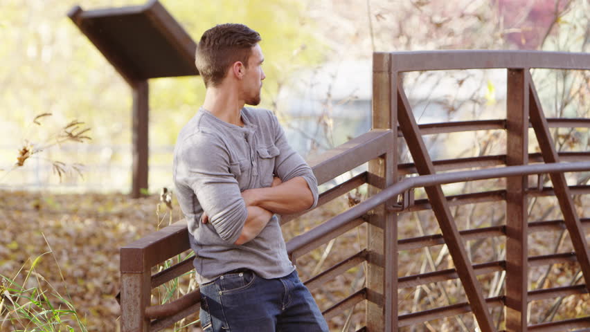 Young man standing on a wood bridge.