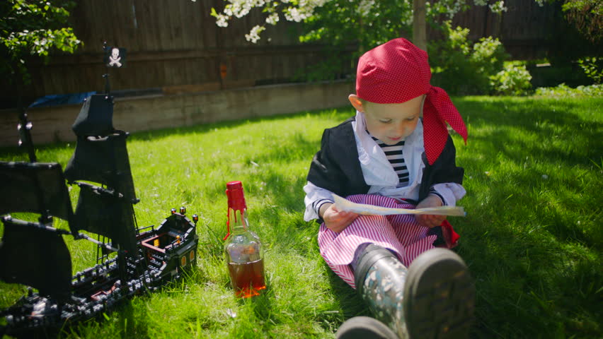 Little pirate exploring treasure map on the lawn