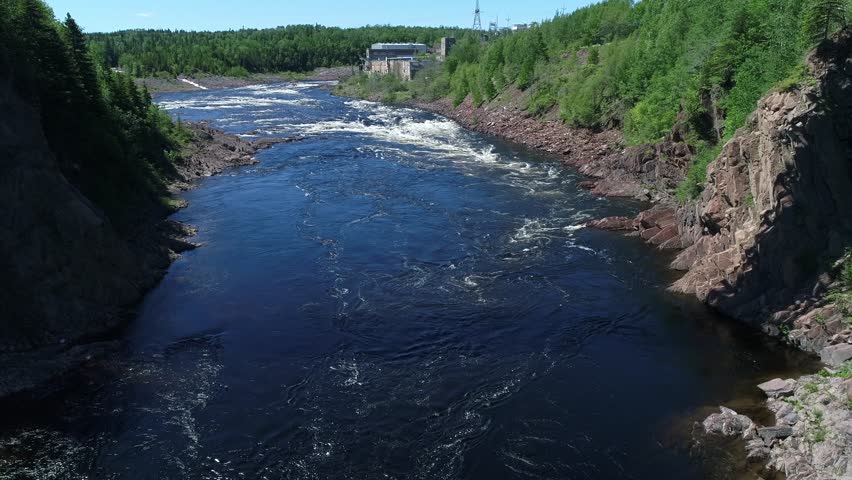 A beautiful aerial shot of a long steel bridge over an amazing wild river and forrest of trees below the hydro electric dam in Grand Falls Windsor Newfoundland Canada