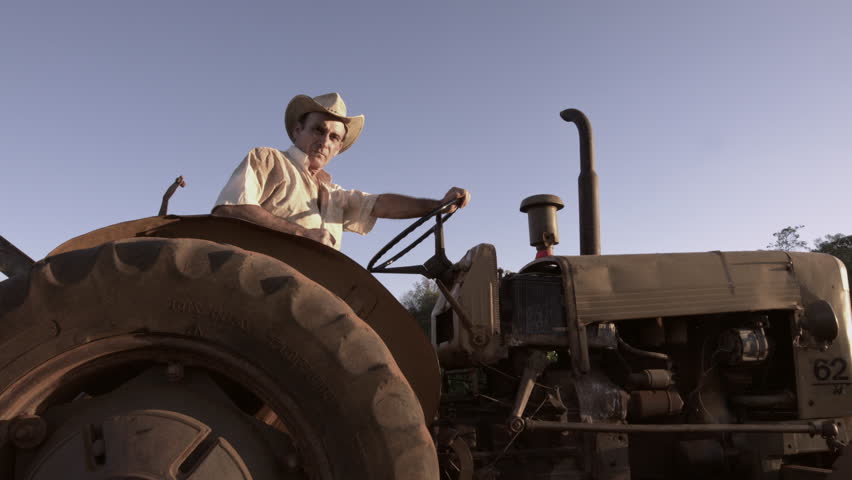 59.94fps (It can be in slow motion) happy farmer with a hat driving tractor. 4K Cinematic. Royalty-Free Stock Footage #30953134