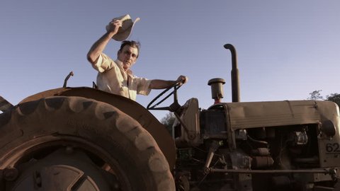 59.94fps (It can be in slow motion) happy farmer with a hat driving tractor. 4K Cinematic.